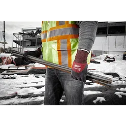 Worker wearing Cut Level 3 Winter Insulated Gloves - XL holds metal rebar at a construction site, dressed in a safety vest.