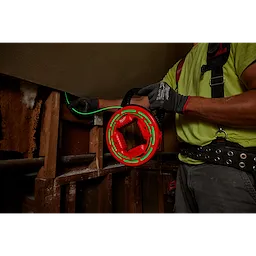 Person using the 40' Glow Fish Tape in a home construction setting; the tape glows green and the reel is red.