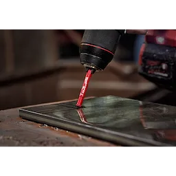A close-up of a power drill using a 1/4" Diamond Grit Hole Saw to drill precise holes in a black tile.