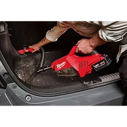 A person uses the M18 Brushless Handheld Vacuum to clean the trunk of a car.