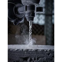 SDS Plus M2 2-Cutter Drill Bits in action, drilling into concrete with dust particles around the bit, attached to a power drill.