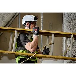 Worker carrying a ladder indoors wearing Cut Level 1 Nitrile Dipped Gloves w/ WEAR-DEFENSE Protection.