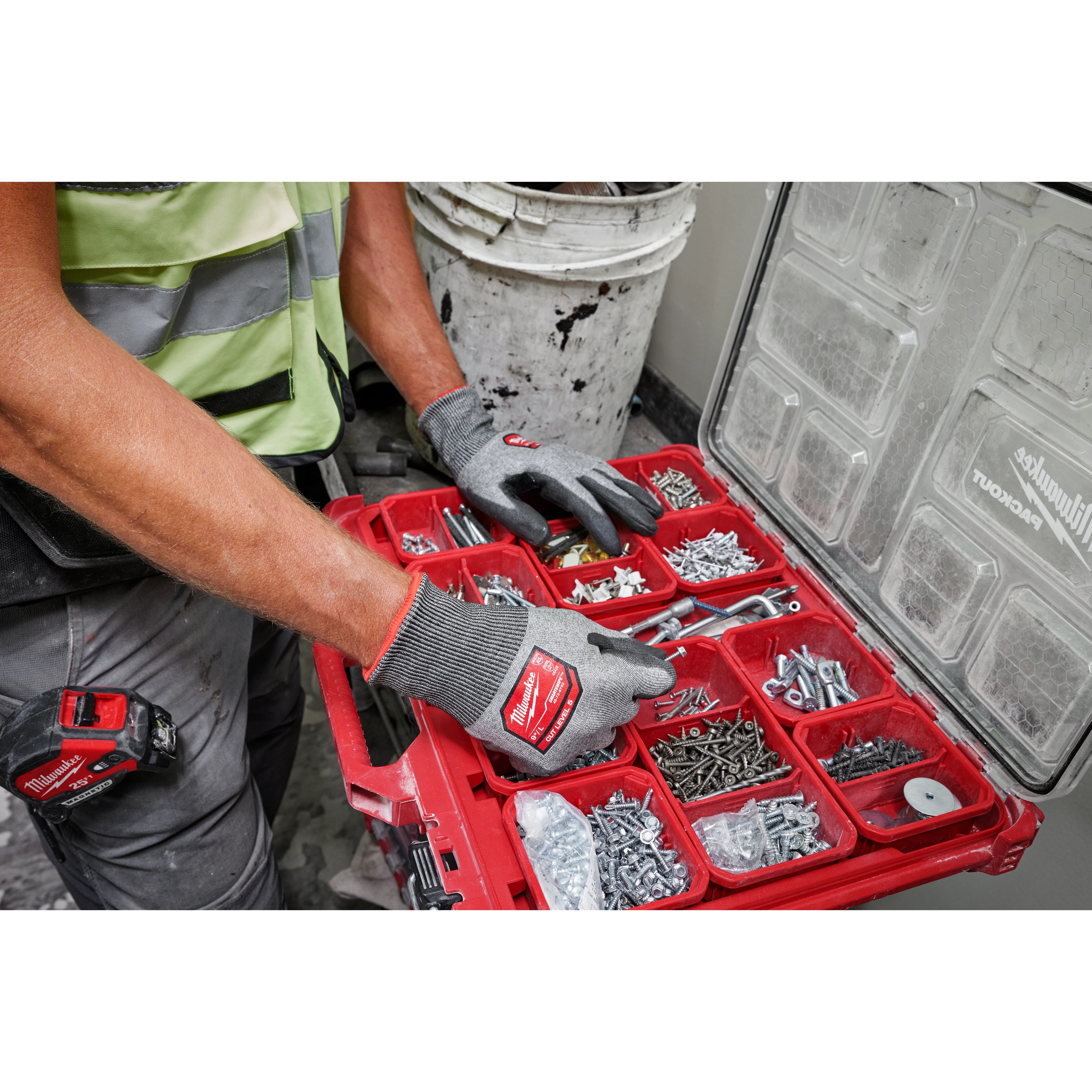 Person wearing Cut Level 5 High Dexterity Polyurethane Dipped Gloves - L, sorting screws and tools in a red organizer box.