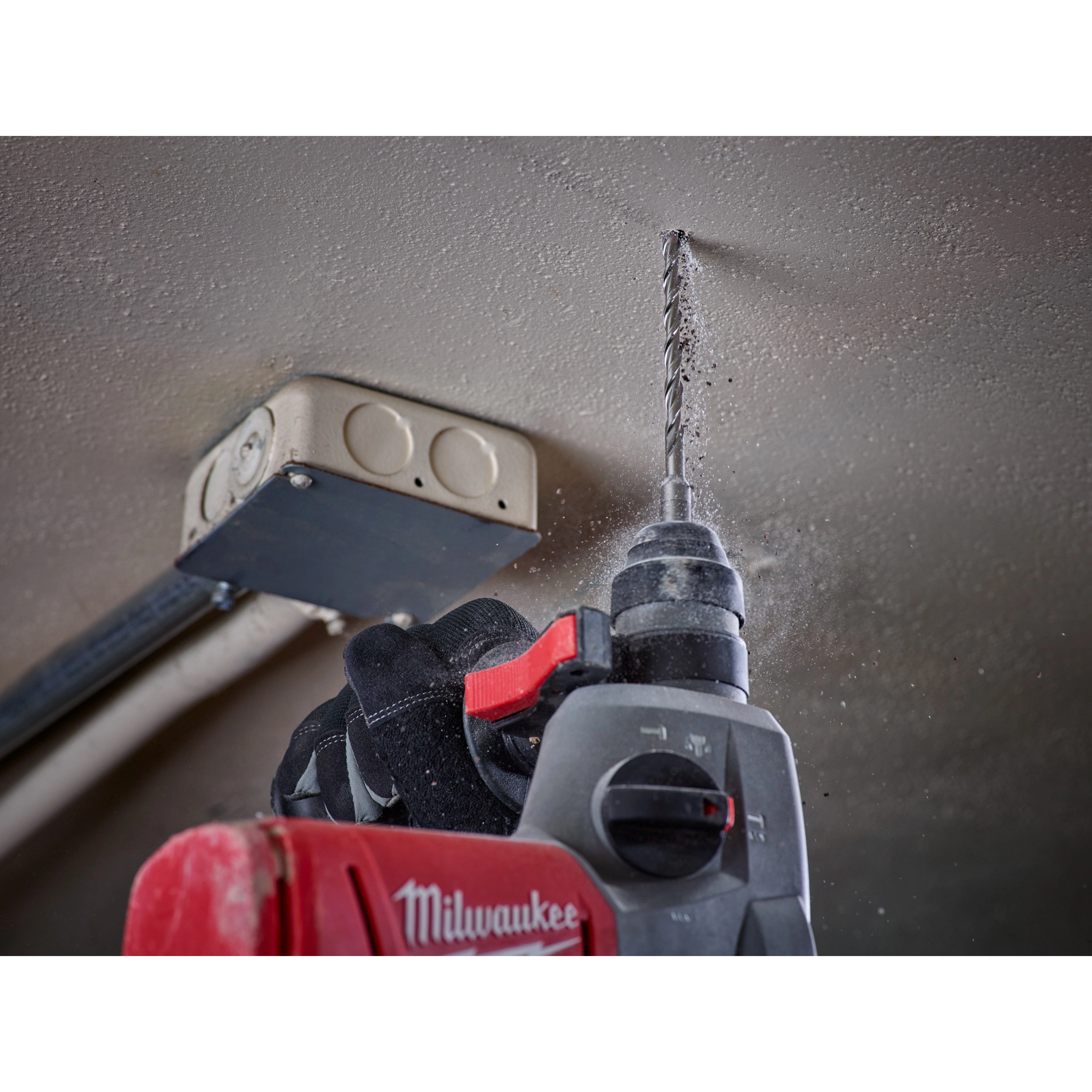 A worker uses SDS Plus M2 2-Cutter Drill Bits with a power drill to make a hole in a ceiling near an electrical box.