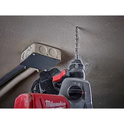 A worker uses SDS Plus M2 2-Cutter Drill Bits with a power drill to make a hole in a ceiling near an electrical box.
