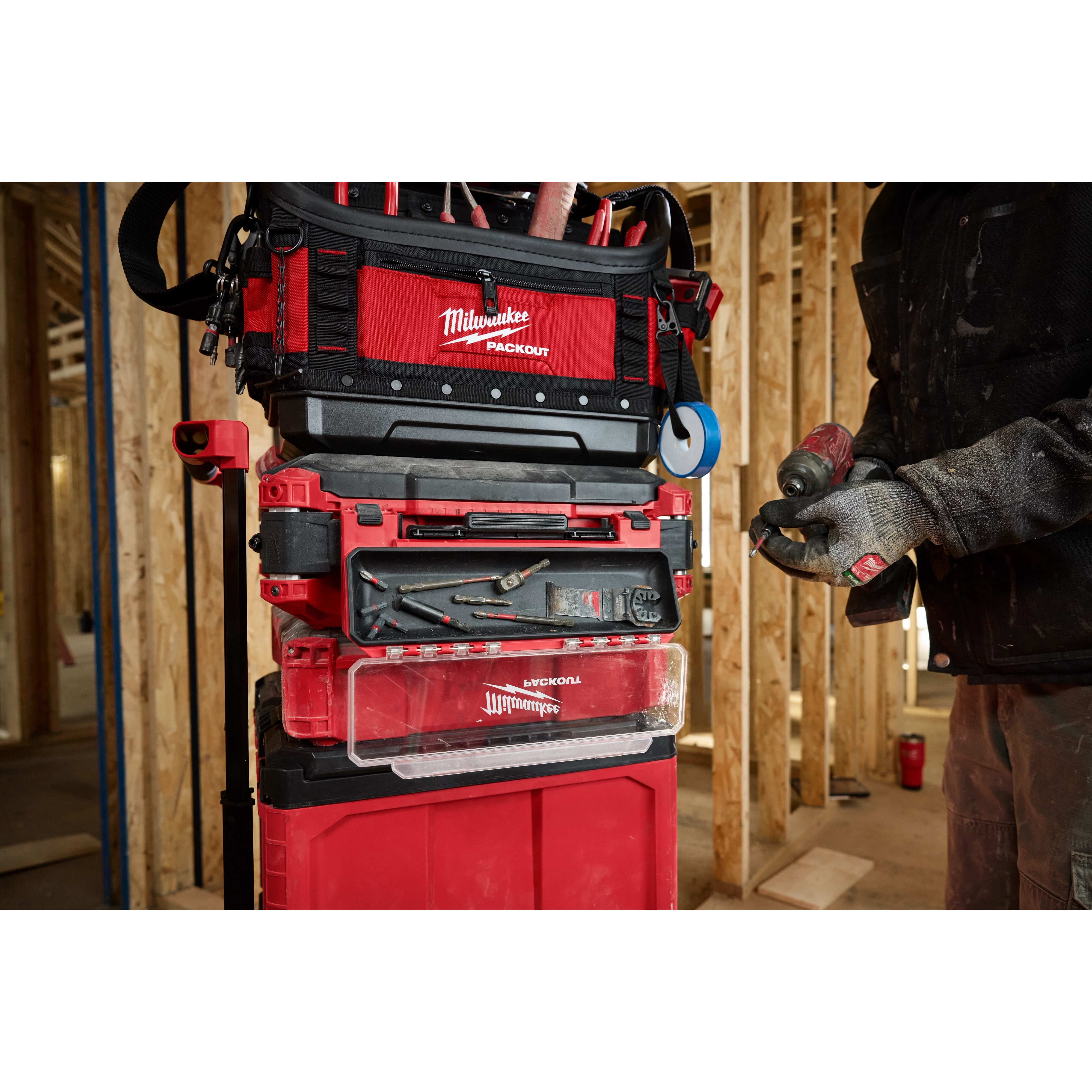 The PACKOUT Tool Box Magnetic Bin Attachment is shown connected to a stack of red and black Milwaukee PACKOUT toolboxes in a workshop.