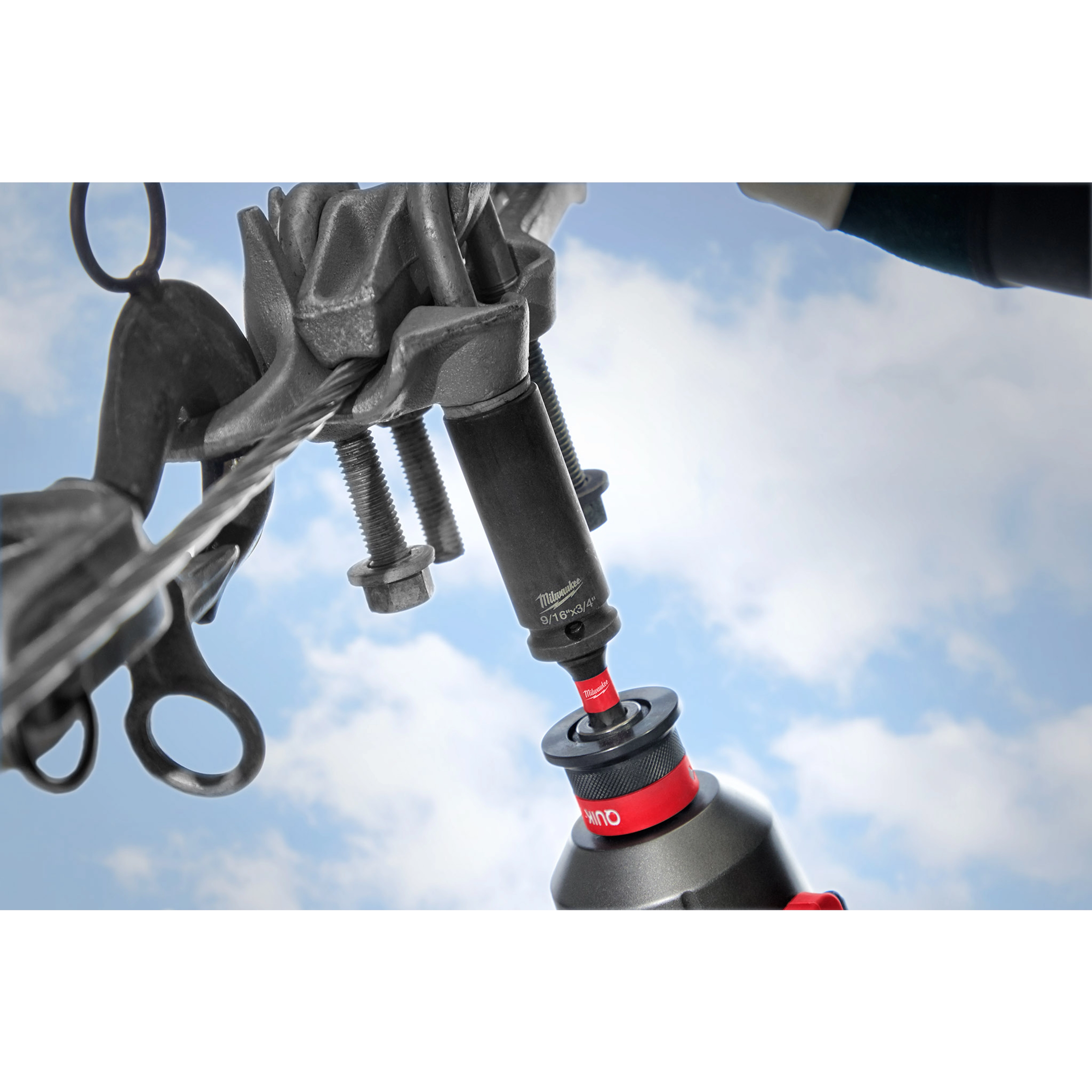 9/16"-3/4" 12PT 2-in-1 Socket connected to a power tool, tightening bolts on a mechanical component against a blue sky background.