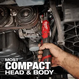 A person is using the M12 FUEL™ 3/8" Ratchet to work on a car engine. The ratchet's red and black design is visible, showing its compact size suitable for tight spaces. Text in the image reads "MOST COMPACT HEAD & BODY."