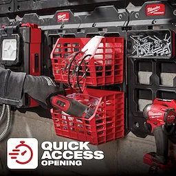 PACKOUT Compact Wall Basket mounted on a wall grid holds various tools and accessories. A hand is placing a tool into the lower basket.