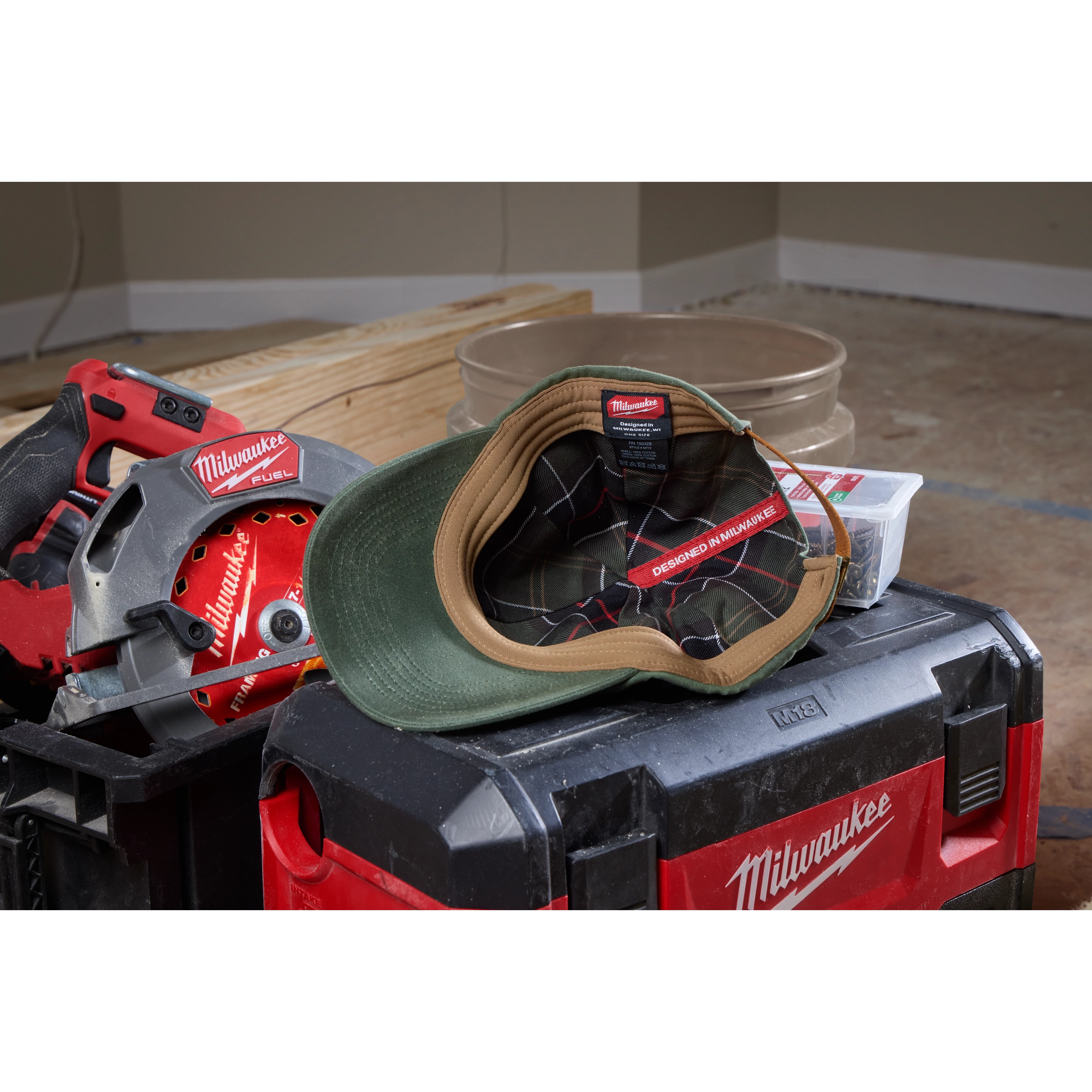 Waxed Canvas Adjustable Hat in green and brown resting on a black and red toolbox with other tools in the background.