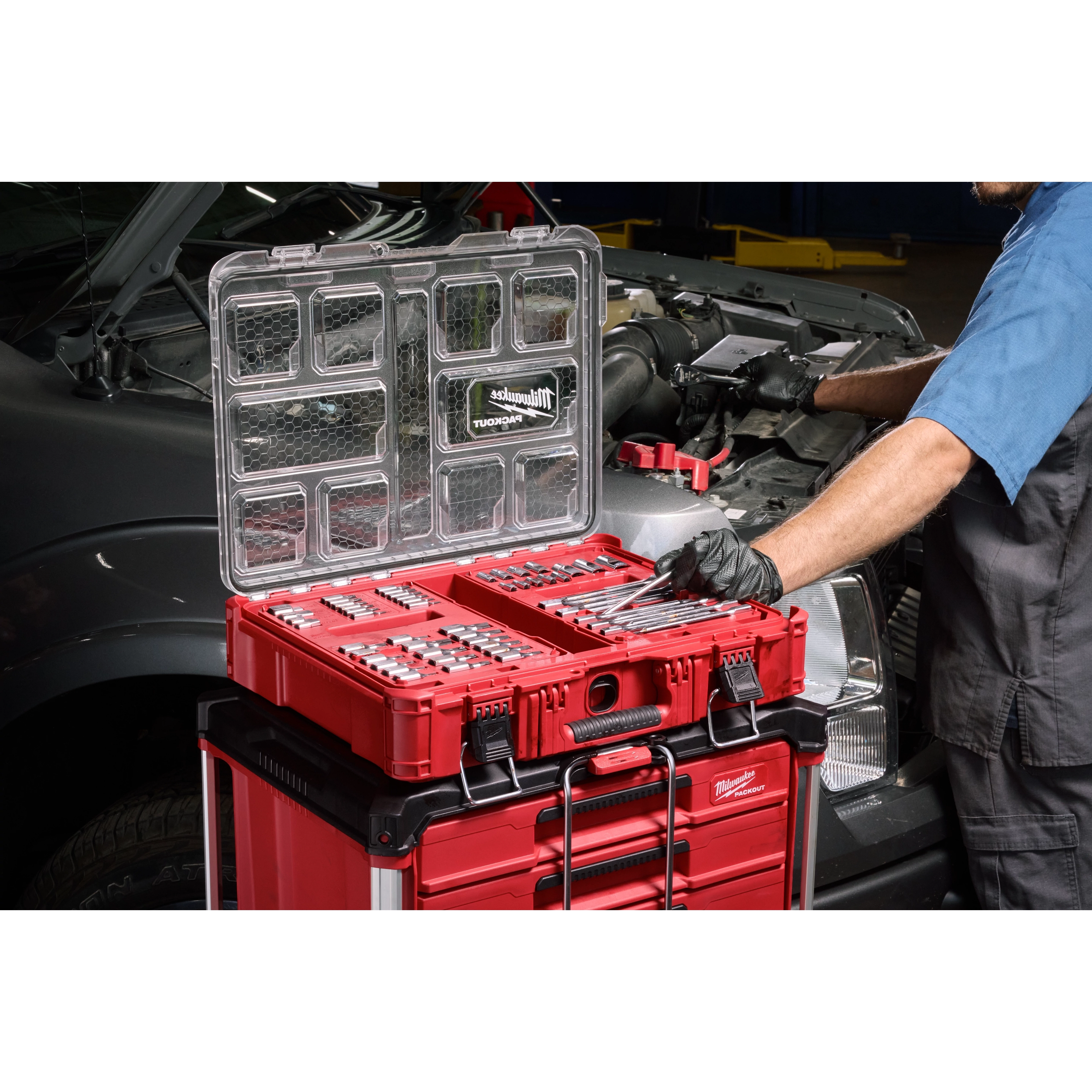 106pc 1/4", 3/8", and 1/2" Drive Bit Socket Set with PACKOUT Organizer open on a red tool stack near a vehicle engine.