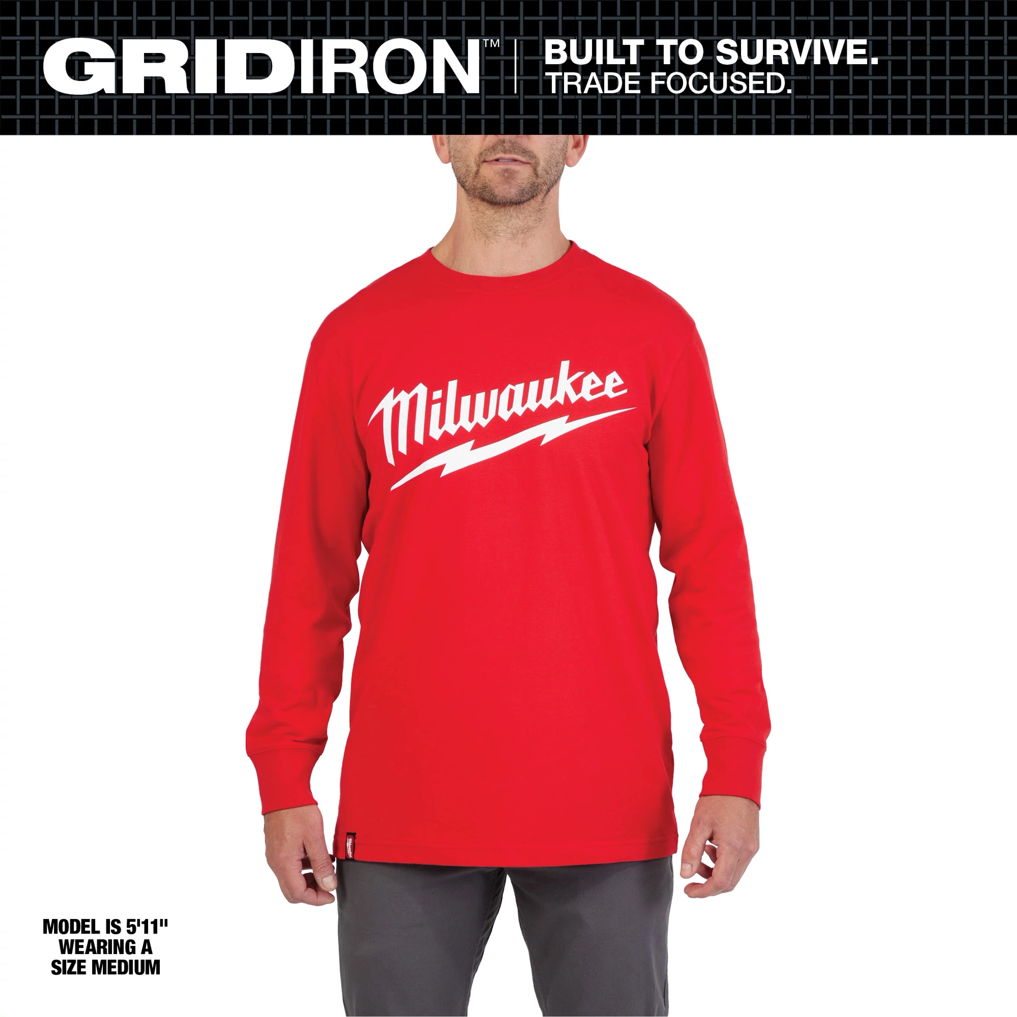 Heavy Duty Tee - Long Sleeve Logo Primary Image displayed in red with white text, worn by a model standing in grey pants.