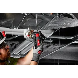 A person is using a 14-in-1 Ratcheting Multi-Bit Screwdriver to tighten a metal panel on a duct system in an industrial setting.