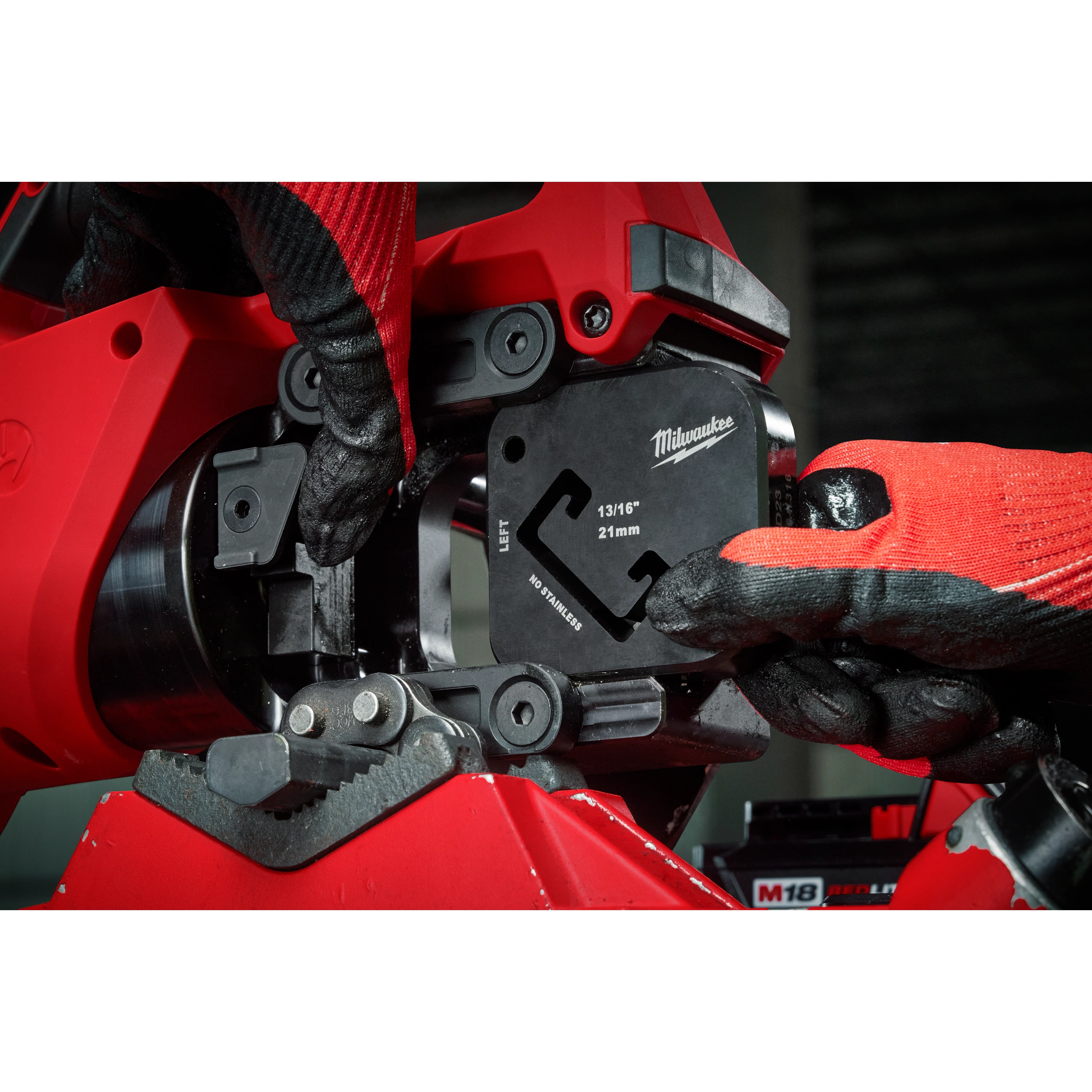 Worker using 13/16" x 1-5/8" Single Strut Shearing Dies in a red industrial machine, wearing red and black gloves.