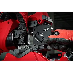 Worker using 13/16" x 1-5/8" Single Strut Shearing Dies in a red industrial machine, wearing red and black gloves.