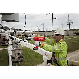A utility worker uses an M18 FORCE LOGIC 6 Ton Pistol Utility Crimper to secure a connection on overhead power lines from a bucket truck.