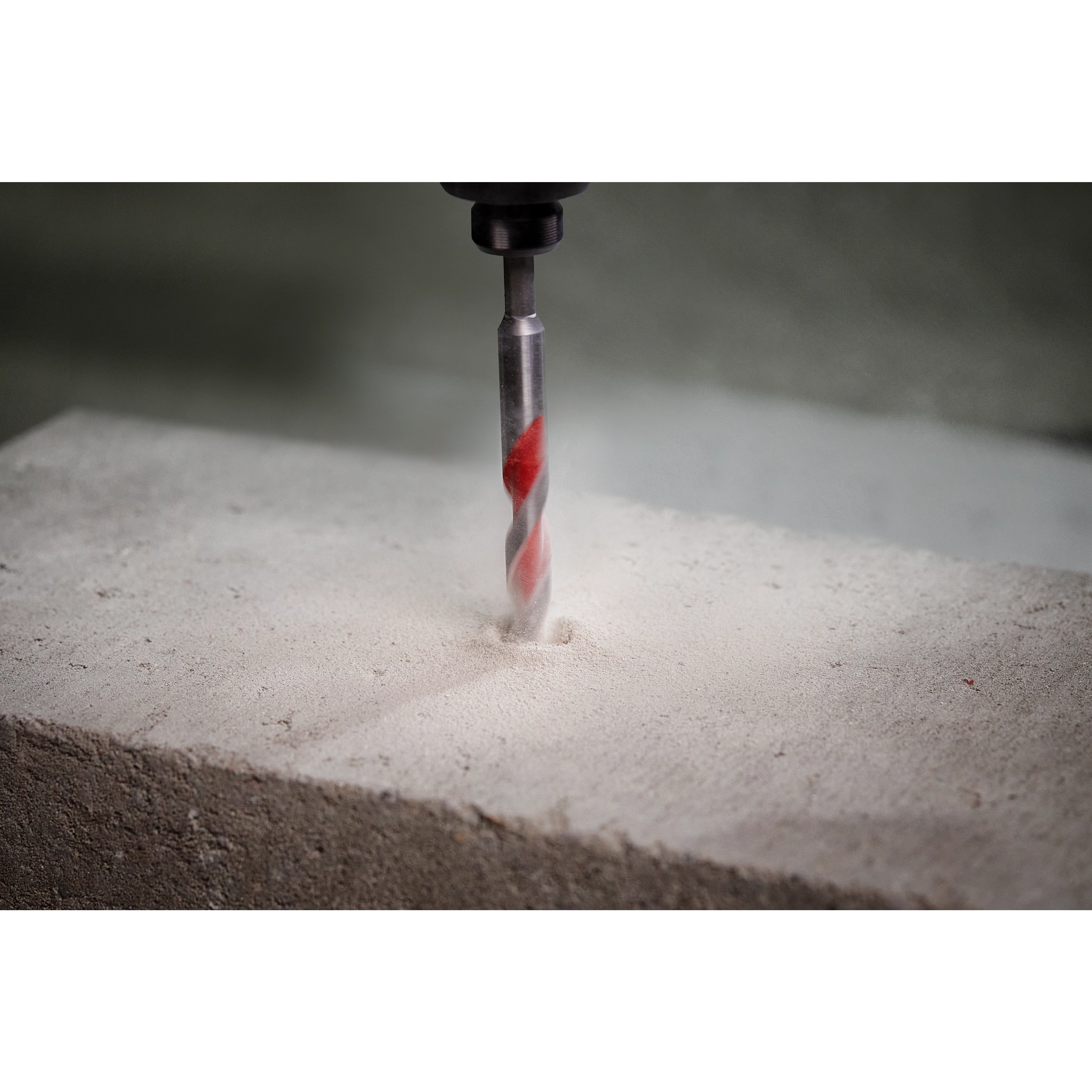 1/2" x 4" x 6" SHOCKWAVE Carbide Hammer Drill Bit drilling into a concrete block, creating a precise, dust-filled hole.