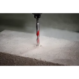 1/2" x 4" x 6" SHOCKWAVE Carbide Hammer Drill Bit drilling into a concrete block, creating a precise, dust-filled hole.
