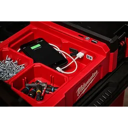 M12 PACKOUT Flood Light with USB Charging shown with various tools, screws, and a phone being charged inside a red tool organizer.