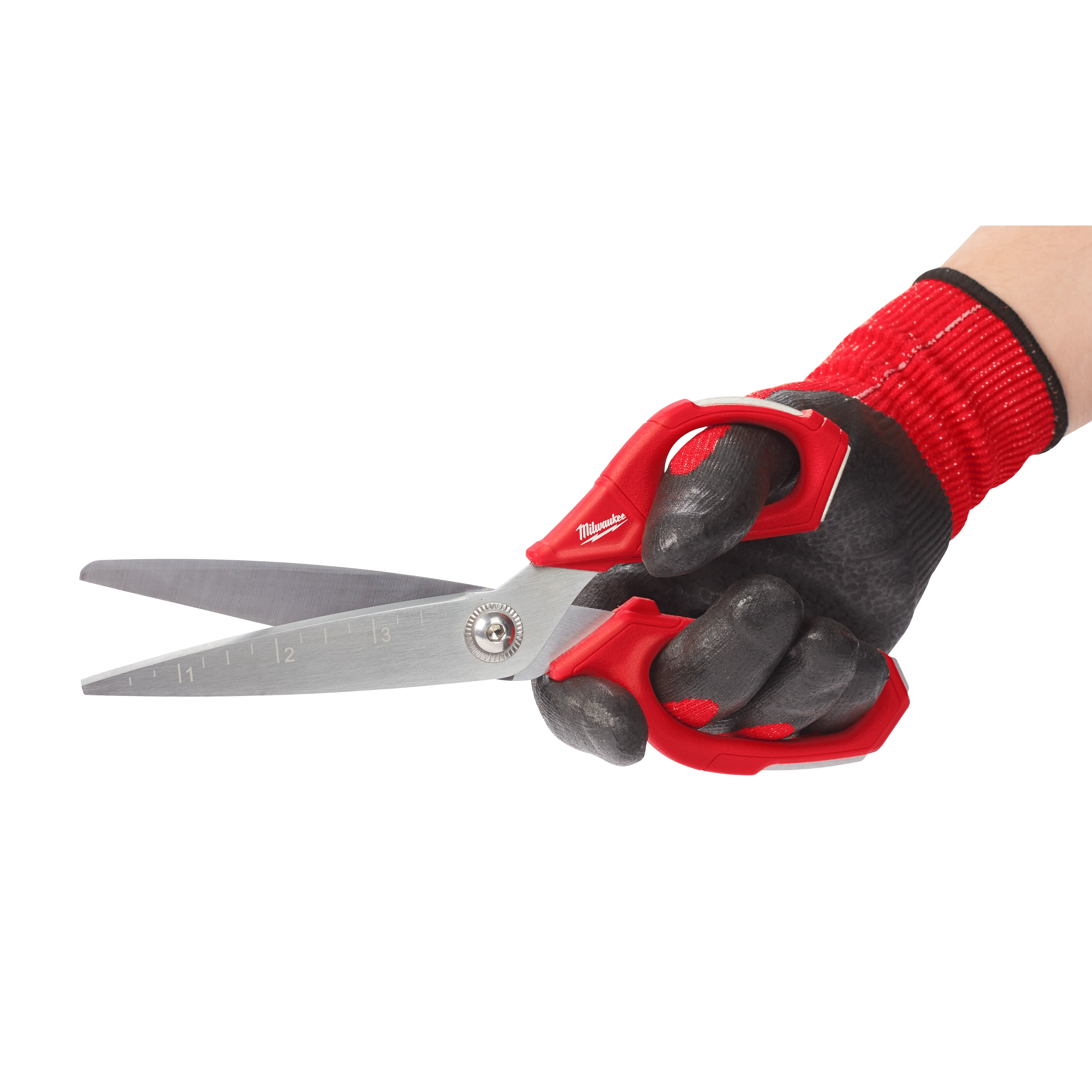 A hand wearing a red and black work glove holds the Offset Jobsite Scissors, which have a red handle and stainless steel blades. The scissors feature measurement markings along one blade.