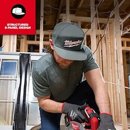A person wearing a Flat Brim Snapback with a structured 5-panel design, positioned in a construction site setting while using a power tool.