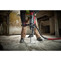 Worker using the SDS-MAX SLEDGE 16" BULL POINT Chisel on a concrete floor, demonstrating its effectiveness for heavy-duty demolition.
