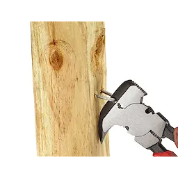 The Comfort Grip Fencing Pliers are shown gripping and pulling a nail from a wooden post. The pliers have a silver head with serrated jaws and red, ergonomic handles.