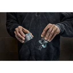 A person holds the Milwaukee Draw Stud tool in their hands, showing the packaged case on the left and the drill bit on the right.