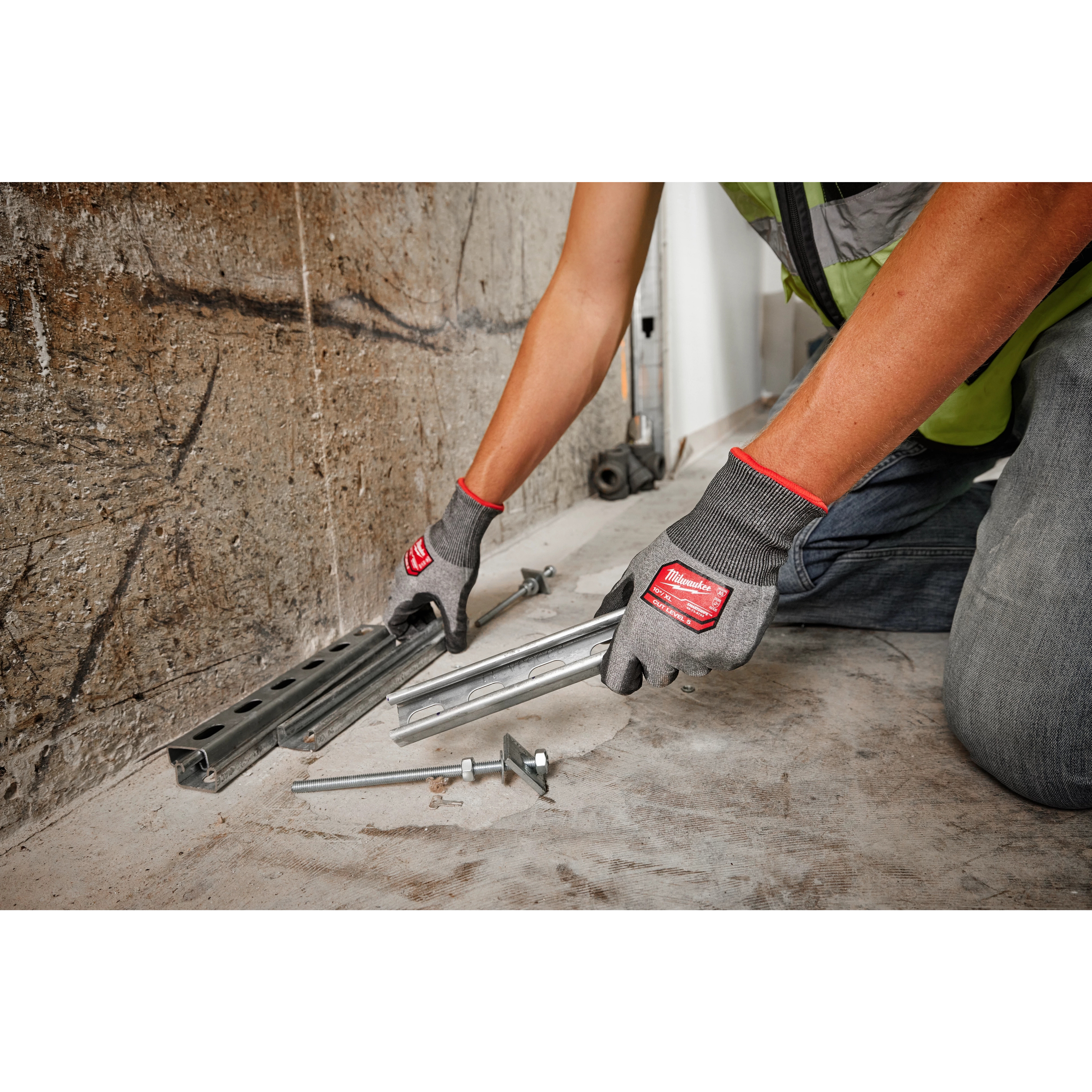 Person wearing Cut Level 5 High Dexterity Polyurethane Dipped Gloves - L handles metal rails and bolts on a concrete floor.