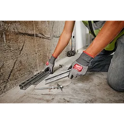 Person wearing Cut Level 5 High Dexterity Polyurethane Dipped Gloves - L handles metal rails and bolts on a concrete floor.