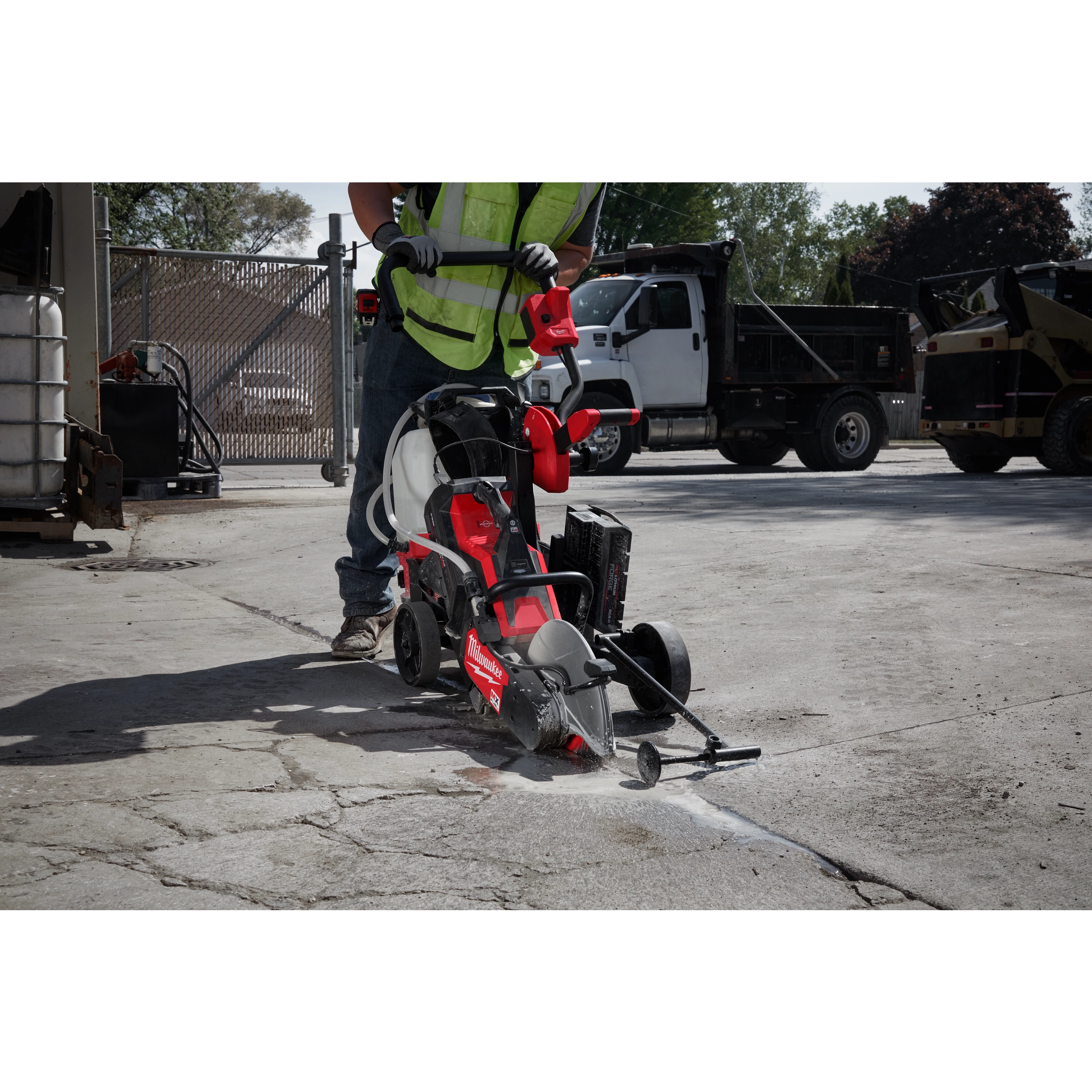 Worker using MX FUEL 14" Cut-Off Saw with RAPIDSTOP to cut concrete outdoors. Saw has red and black design, and blade guard.