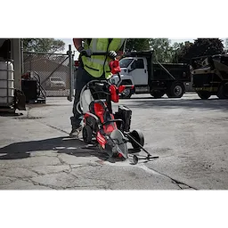 Worker using MX FUEL 14" Cut-Off Saw with RAPIDSTOP to cut concrete outdoors. Saw has red and black design, and blade guard.
