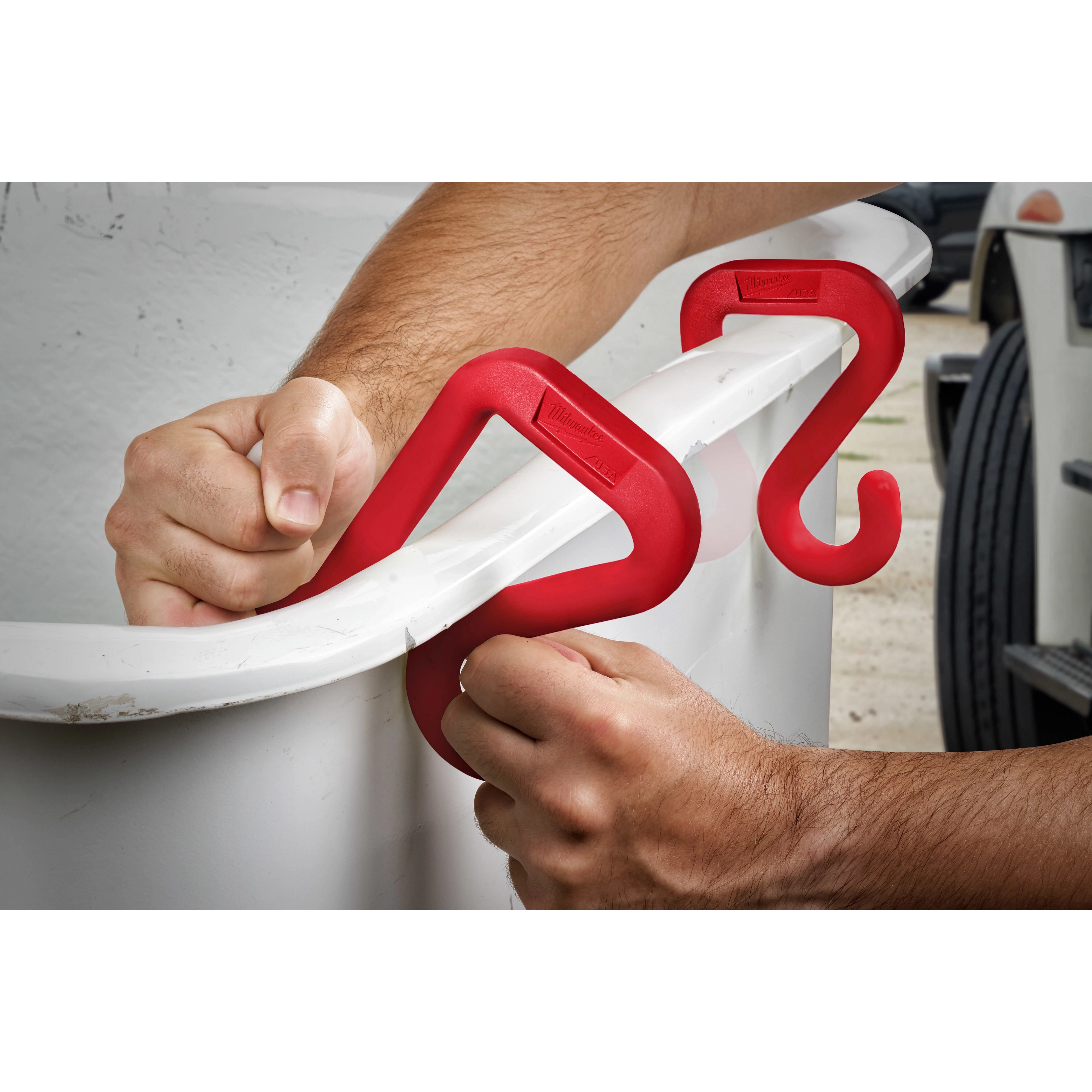 Red 2" Bucket Hook securely attached to the rim of a white bucket, with a person’s hands gripping and demonstrating its use.