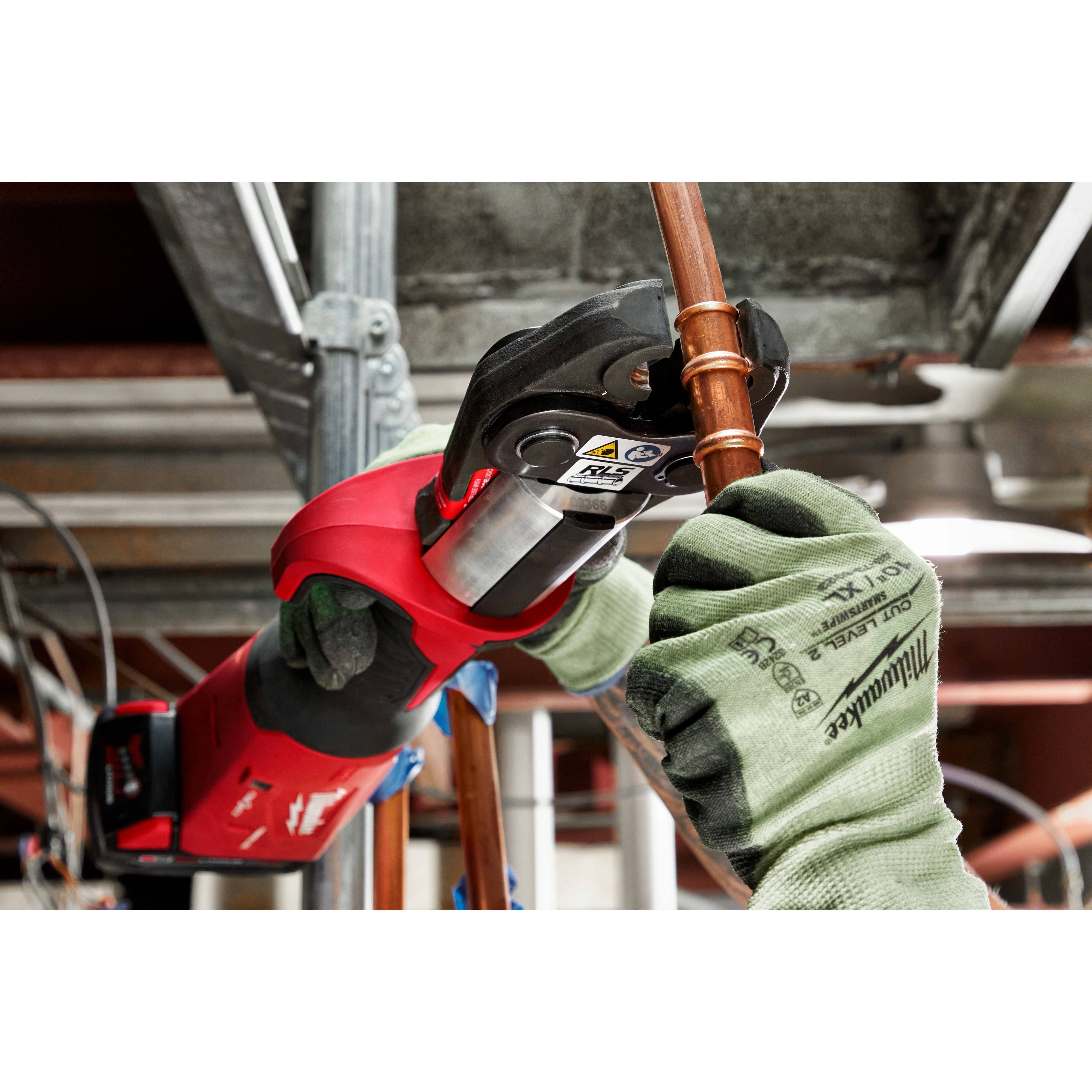 A person using RLS ACR Press Jaws for M18 FORCE LOGIC Press Tools to secure copper piping in an industrial setting.