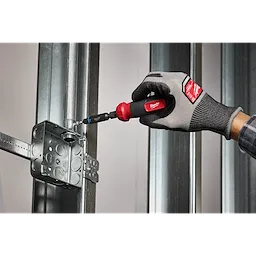 A hand using the Milwaukee 8-IN-1 Multi-Bit & Nut Driver with SHOCKWAVE Impact Duty Bits & Nut Drivers to secure a metal screw into an electrical box mounted on a metal frame.