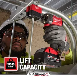 A person uses the SHOCKWAVE™ Impact Duty 3/8" Threaded Rod Nut Runner by Milwaukee, showing its capacity to lift 100 lbs. The tool is held in a gloved hand.