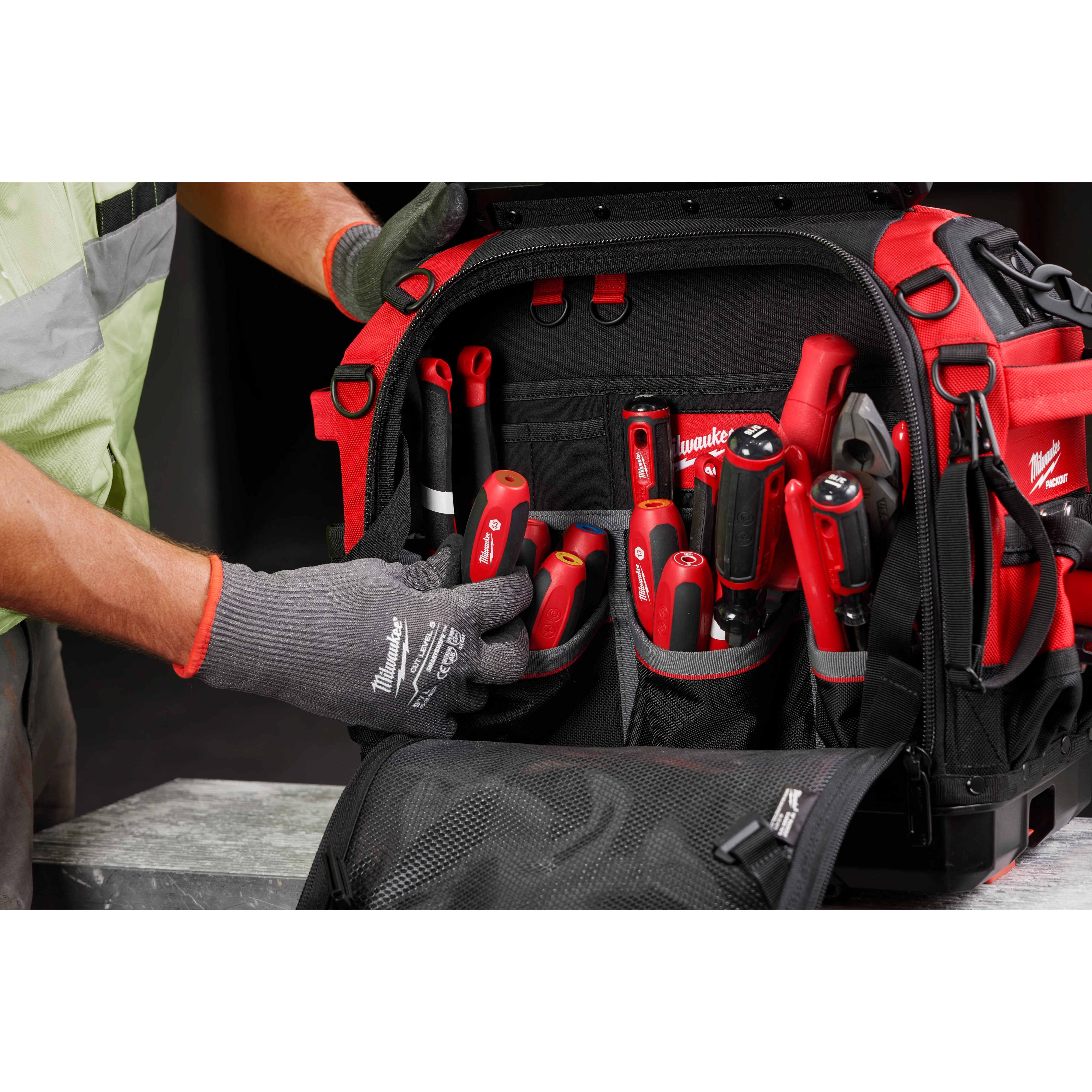 Worker organizing a black and red tool bag filled with a 7pc Metric HollowCore Magnetic Nut Driver Set and a 7pc Metric HollowCore Nut Driver Set.