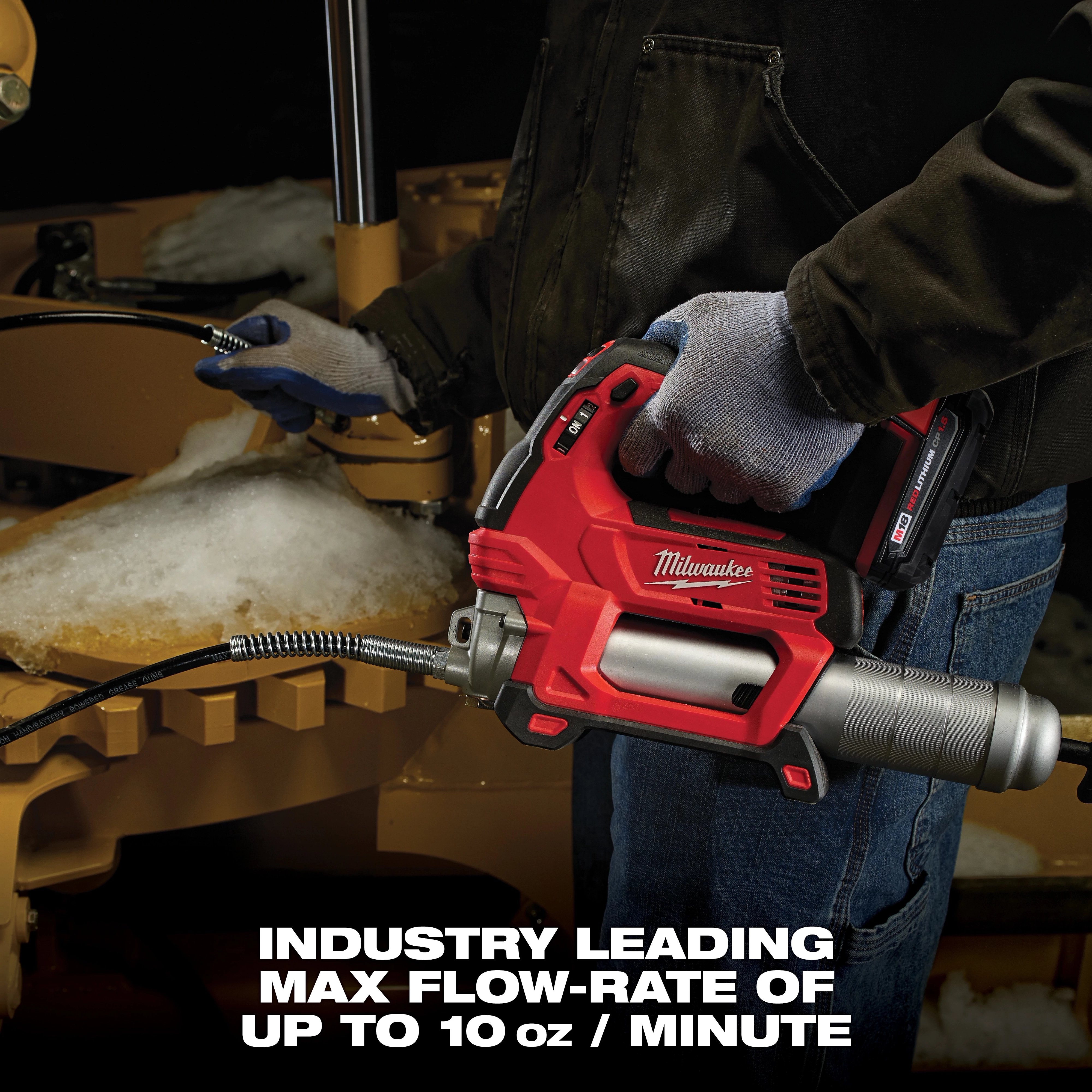 A person in gloves operates a Milwaukee power tool, specifically a cordless grease gun, in a workshop. The text at the bottom reads, "INDUSTRY LEADING MAX FLOW-RATE OF UP TO 10 oz / MINUTE." Snow is visible on the equipment being serviced.
