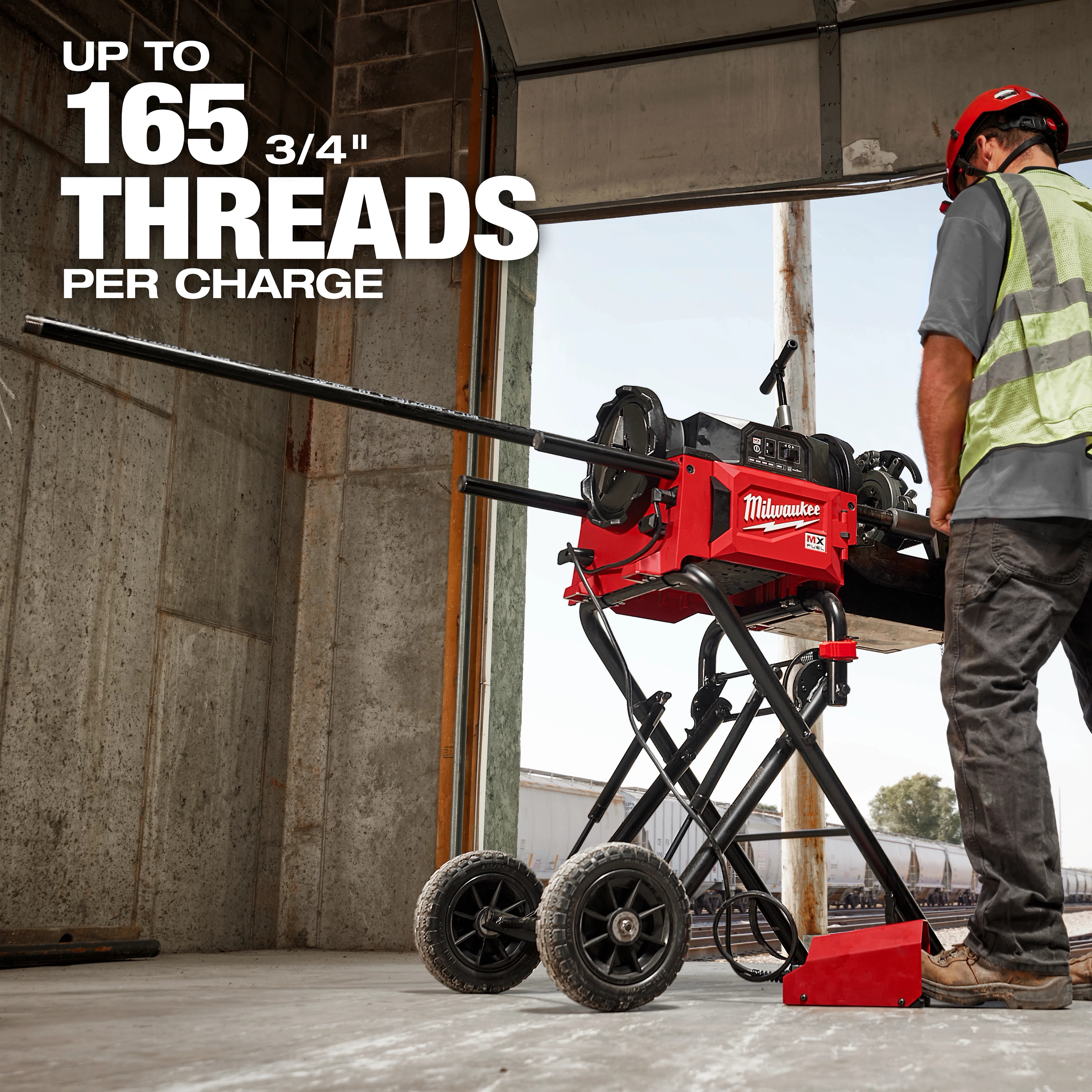 A worker operates the red MX FUEL™ Pipe Threading Machine, which can thread up to 165 3/4" pipes per charge. The machine is mounted on a wheeled stand, making it portable. White text emphasizes the threading capability, and the worker is wearing safety gear, including a hard hat and high-visibility vest.