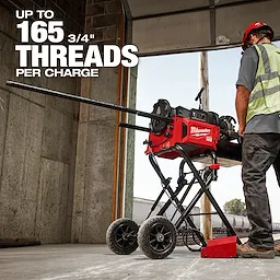 A worker operates the red MX FUEL™ Pipe Threading Machine, which can thread up to 165 3/4" pipes per charge. The machine is mounted on a wheeled stand, making it portable. White text emphasizes the threading capability, and the worker is wearing safety gear, including a hard hat and high-visibility vest.