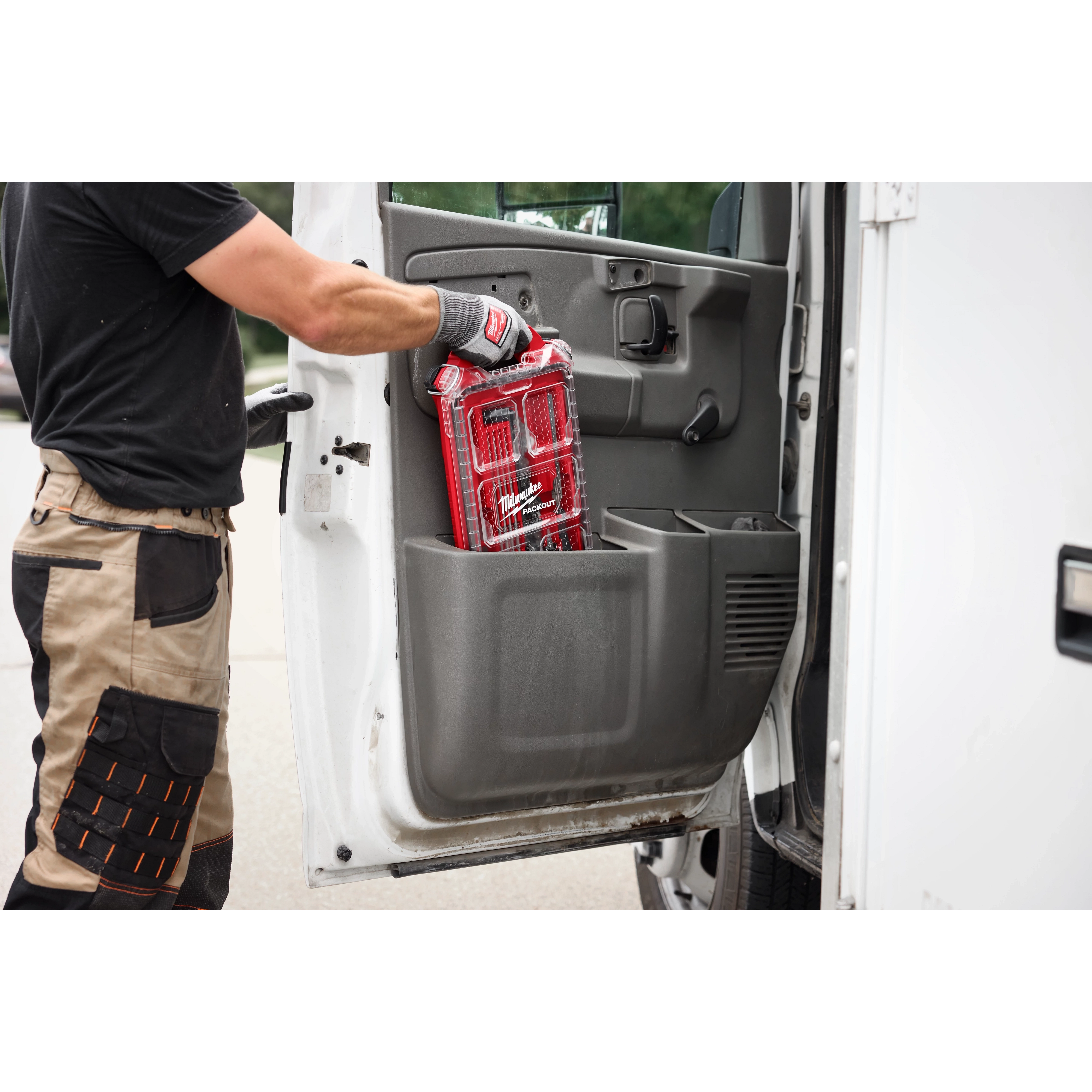 A person in workwear is placing a package of 5/32” Round File for Saw Chain 6 PK inside a truck's door compartment.