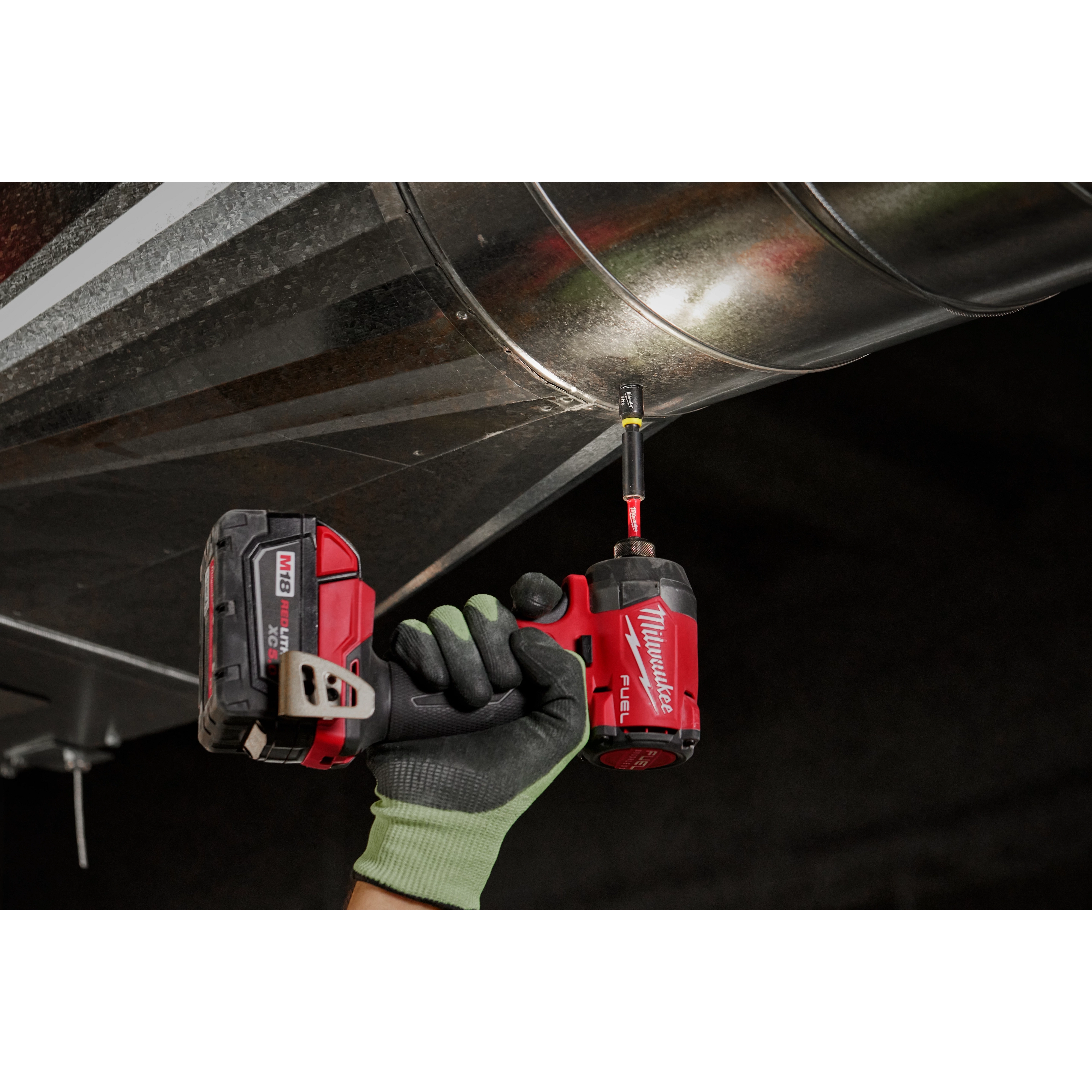 A gloved hand uses a red cordless drill with a SHOCKWAVE 5/16” Insert Magnetic Nut Driver 3PK to secure a metal duct.