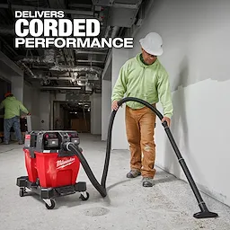 The image features a worker using the Milwaukee M18 FUEL™ NEXUS™ 9 Gallon Dual-Battery Wet/Dry Vacuum in a construction environment. The red vacuum is positioned on a concrete floor, and the worker is holding the vacuum hose. Text stating it "Delivers Corded Performance" is displayed.