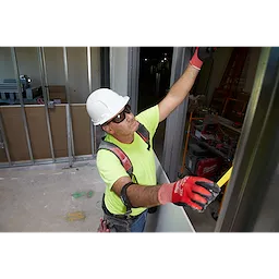 Construction worker wearing Safety Glasses - Gray Fog-Free Lenses, a hard hat, and safety harness installing drywall indoors.