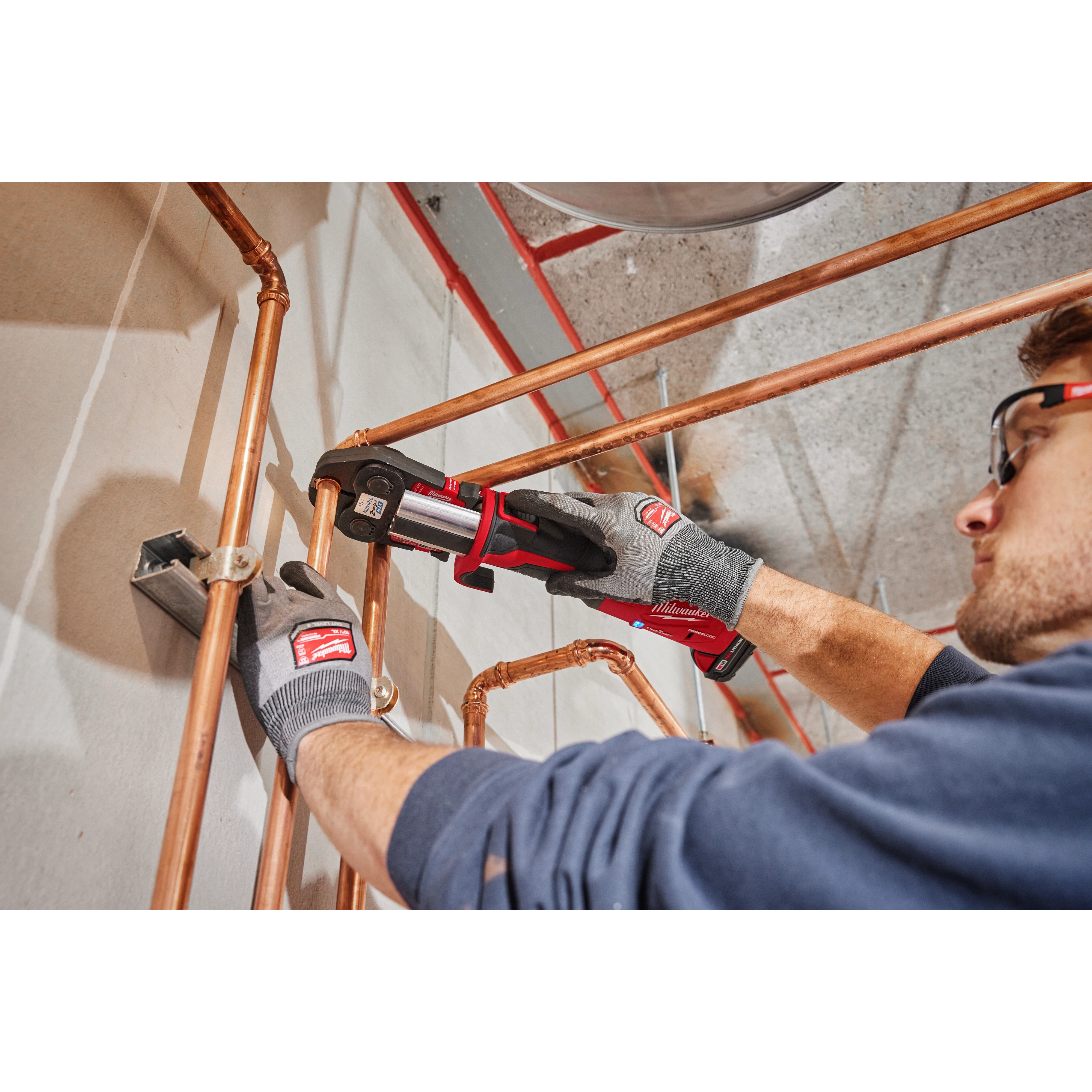 A person uses the 1-1/8" ZoomLock MAX Press Jaw for M18 FORCE LOGIC Press Tools on copper plumbing pipes.