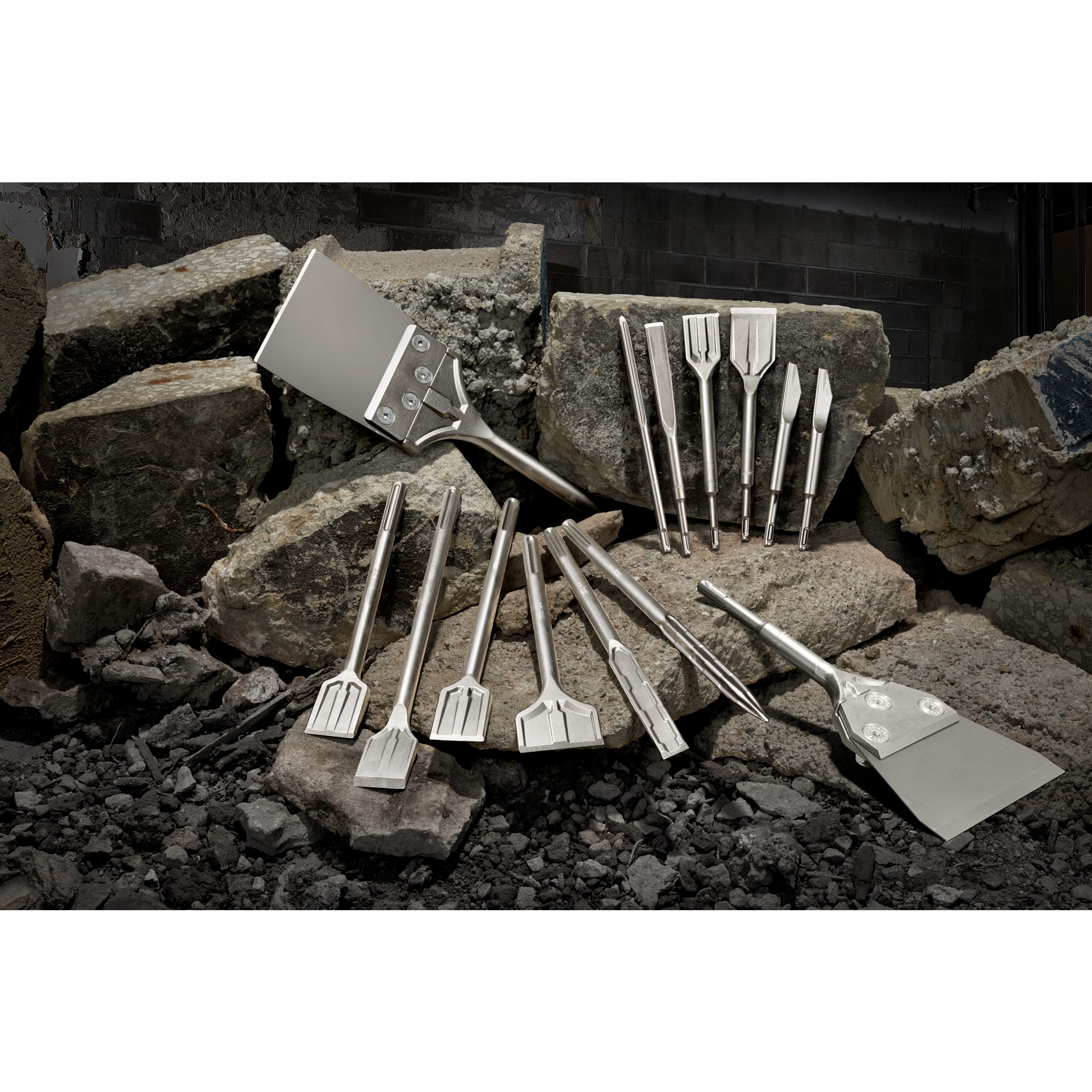 August 2023 Sledge Chisel Family Shot showing various sizes and types of chisels arranged on rocks in a construction setting.