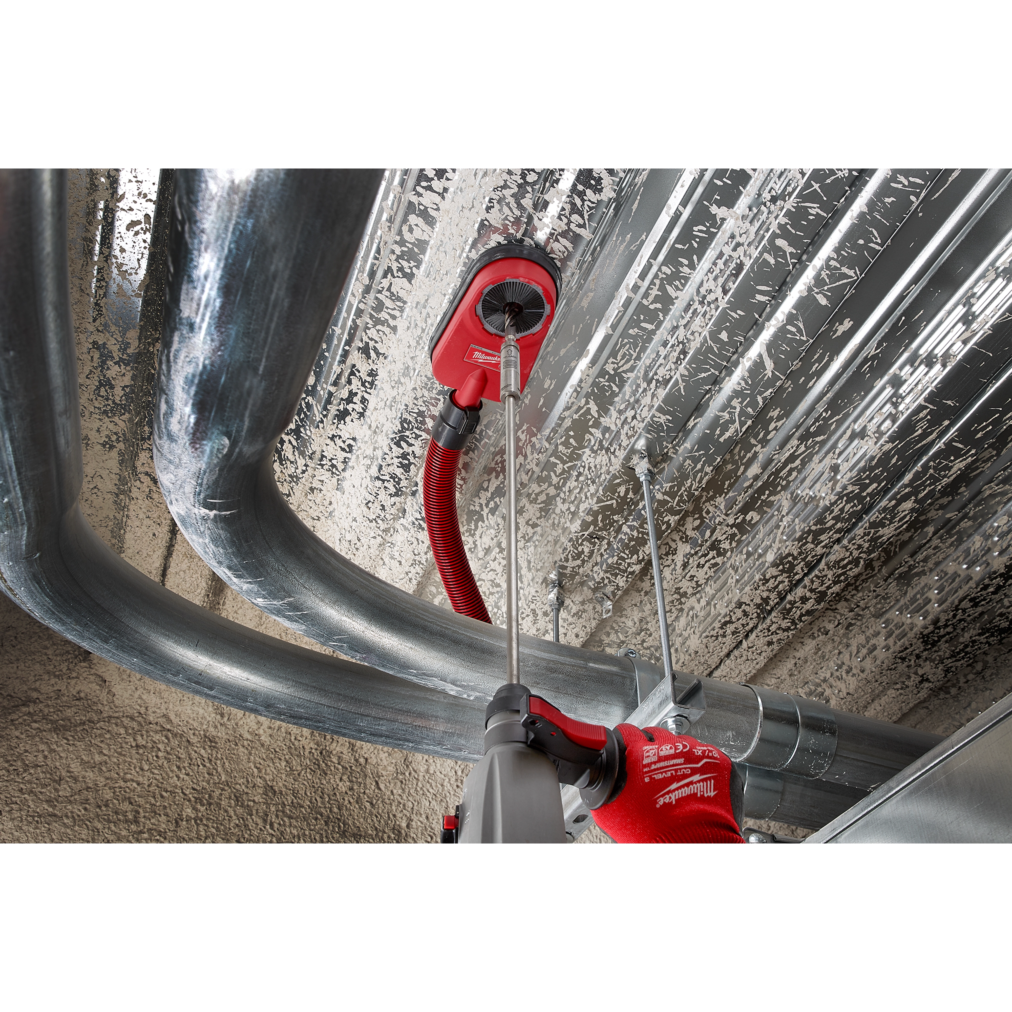 Worker using SDS PLUS 18” EXTENSION to drill into a metal ceiling. Red gloves and vacuum attachment for debris removal are visible.