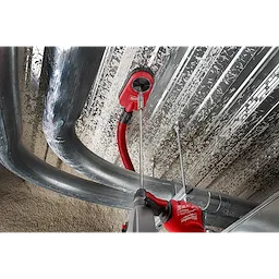 Worker using SDS PLUS 18” EXTENSION to drill into a metal ceiling. Red gloves and vacuum attachment for debris removal are visible.