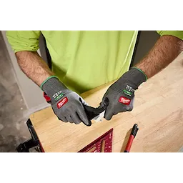 Hands wearing Cut Level 6 High Dexterity Nitrile Dipped Gloves w/ WEAR-DEFENSE Protection working on a wooden surface.