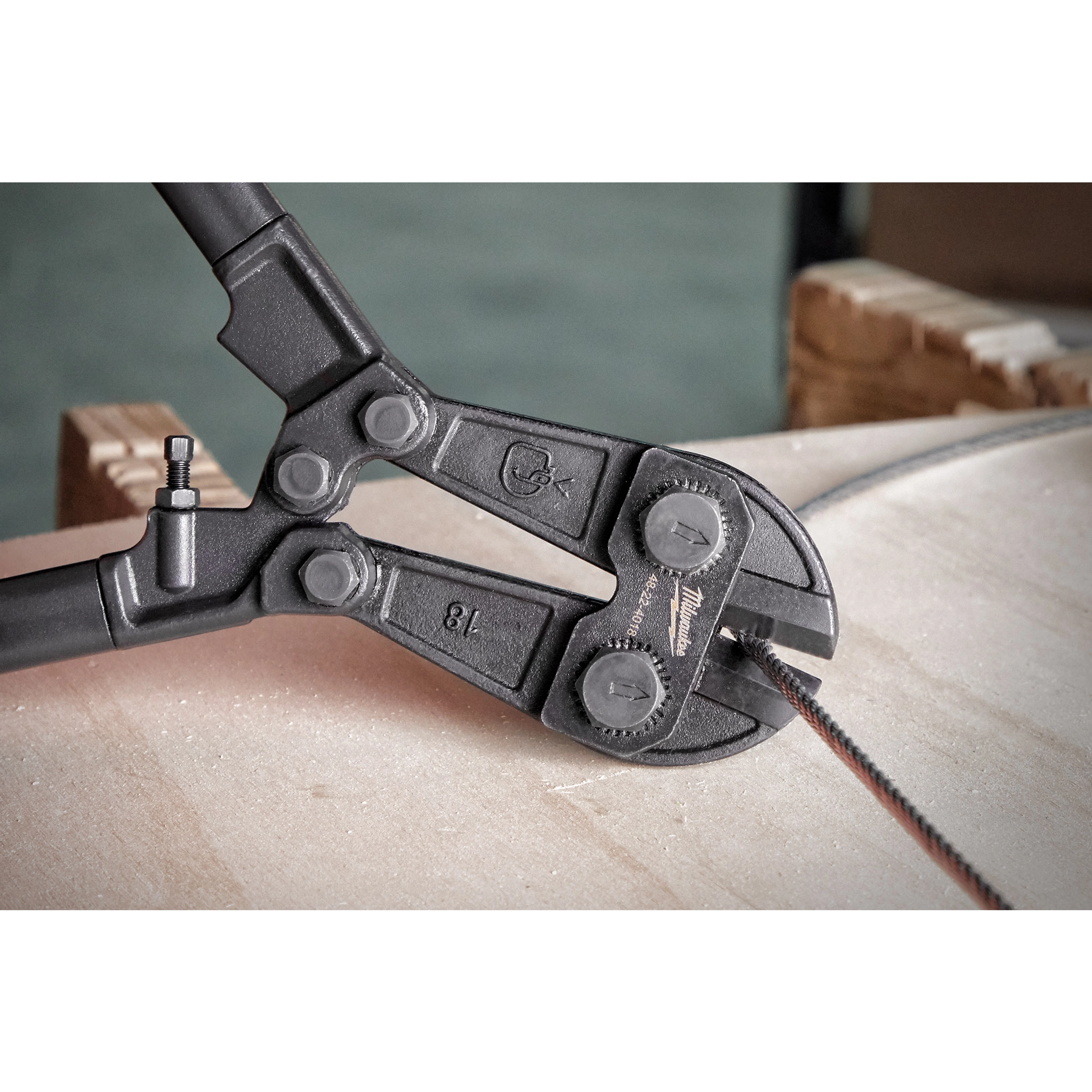 18" Bolt Cutter with black handles cutting through a thick metal cable atop a light-colored surface.